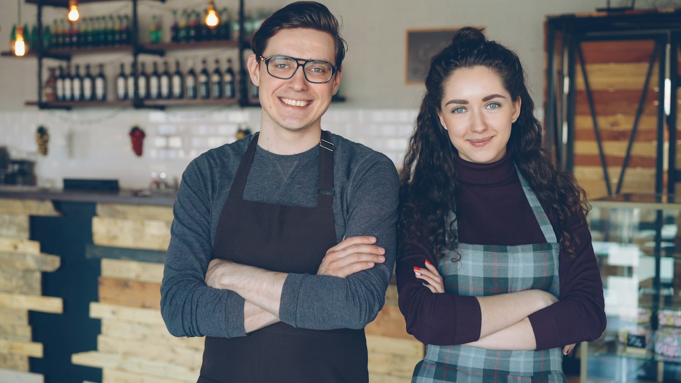 Two cafe owners standing behind their counter